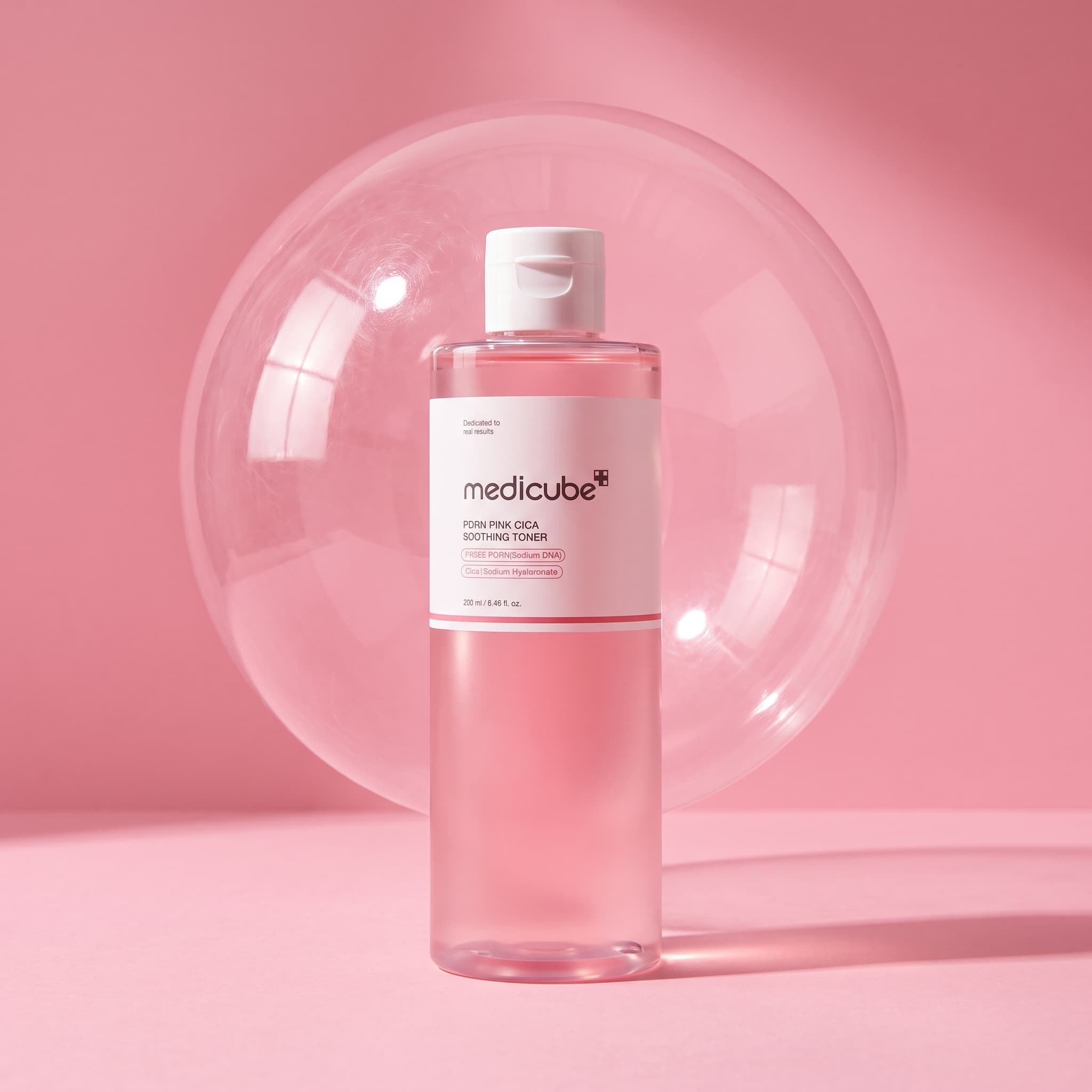 Pink toner bottle on a pink seamless backdrop with a large clear sphere behind it, made with Nano Banana Pro
