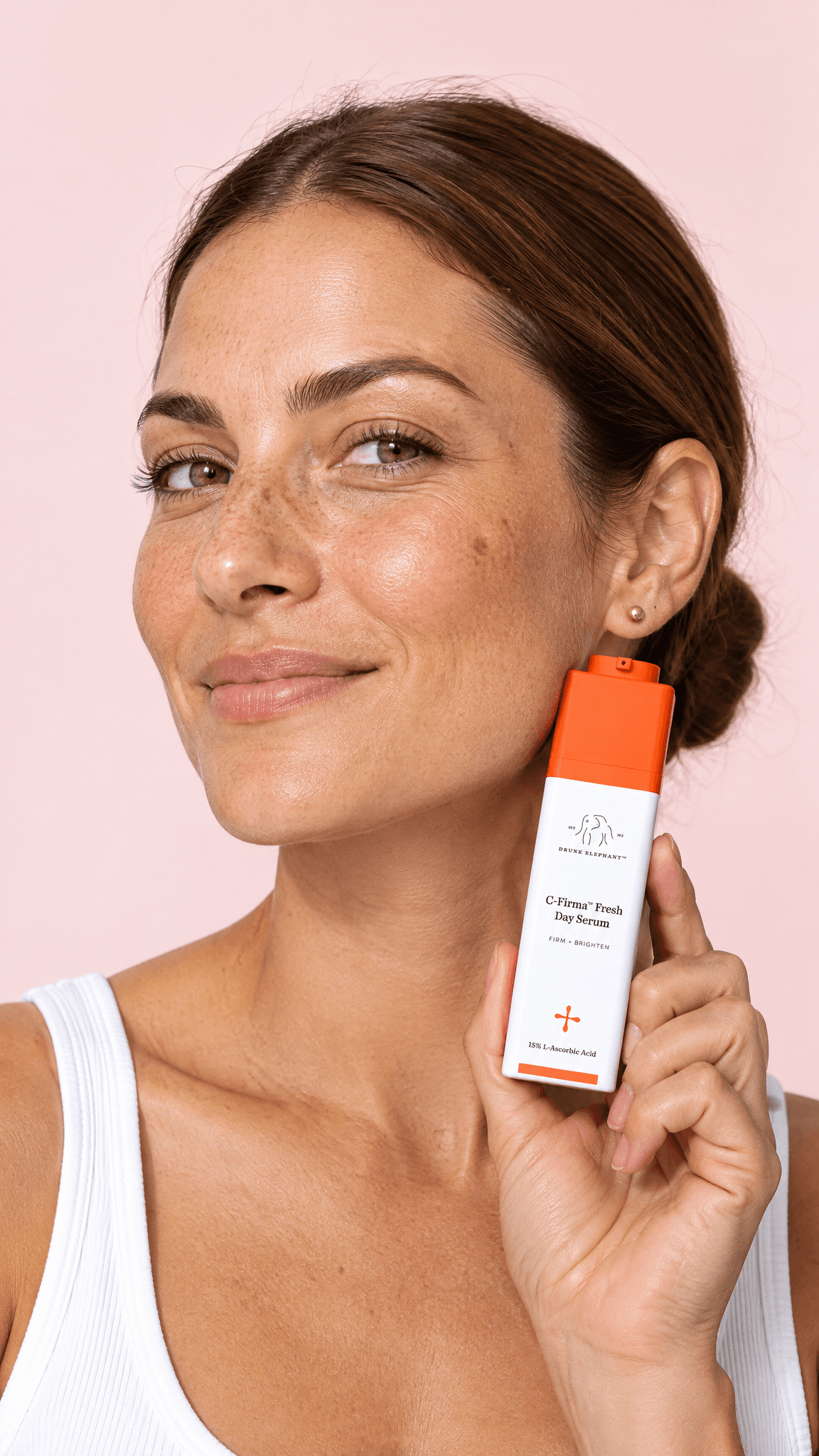 Freckled woman holding the Drunk Elephant C-Firma serum by her jaw on a pink backdrop, made with GPT Image 2.5 Flare