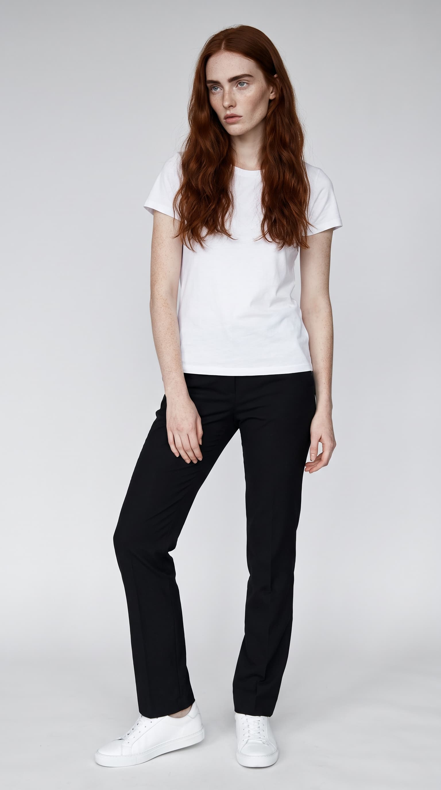 Editorial model with long copper waves and dense freckles in a white tee on grey paper, made with Nano Banana Pro