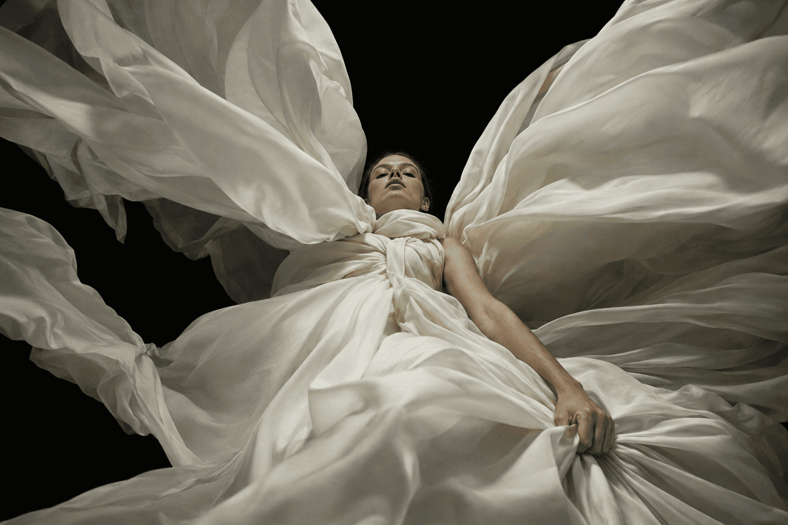 Woman wrapped in smooth ivory silk wings seen from directly below against black, made with GPT Image 2.5 Sunburst