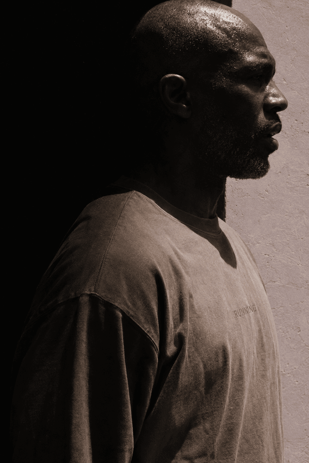 Man in strict profile, back of his head fading into black, mauve wall in front of him, made with GPT Image 2.5 Sunburst
