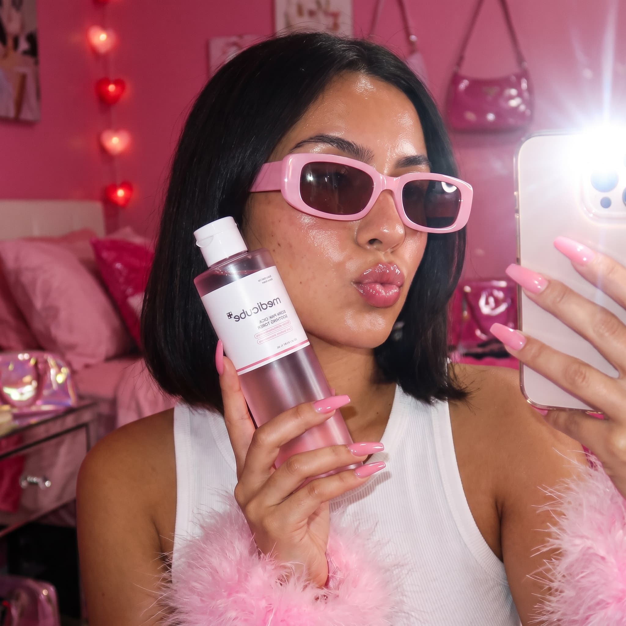 Flash mirror selfie of a woman in pink sunglasses holding a pink toner bottle in a pink bedroom, made with Nano Banana Pro